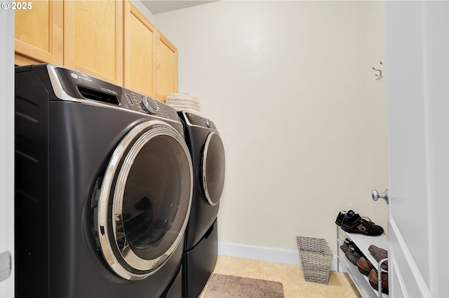 laundry area featuring cabinets, light tile patterned floors, and washer and dryer