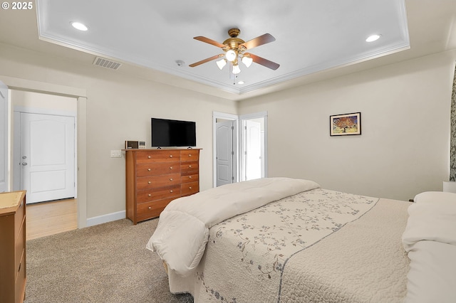 carpeted bedroom with a tray ceiling, ornamental molding, and ceiling fan