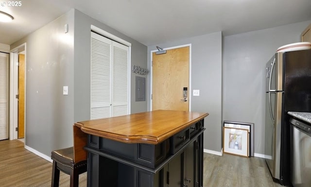 kitchen featuring dark cabinets, stainless steel appliances, wood finished floors, baseboards, and electric panel