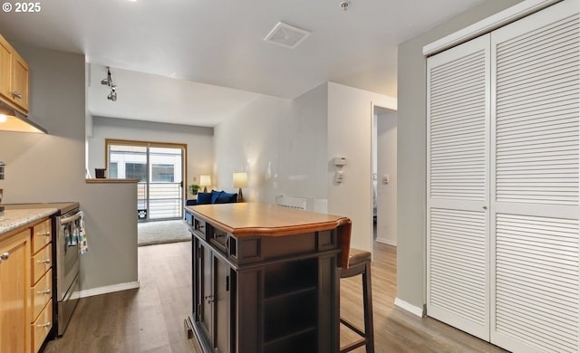 kitchen with dark wood-style flooring, light countertops, stainless steel electric range oven, and baseboards