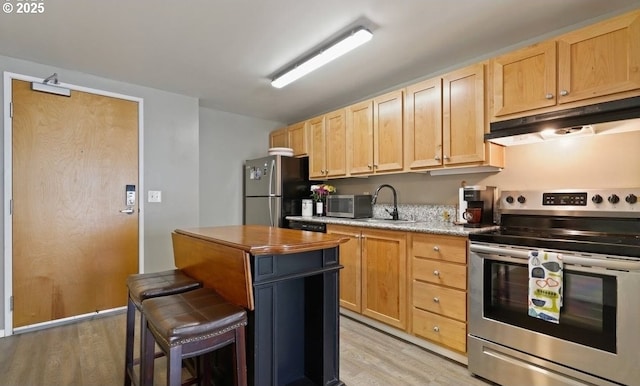 kitchen featuring appliances with stainless steel finishes, light wood-type flooring, under cabinet range hood, and light brown cabinetry