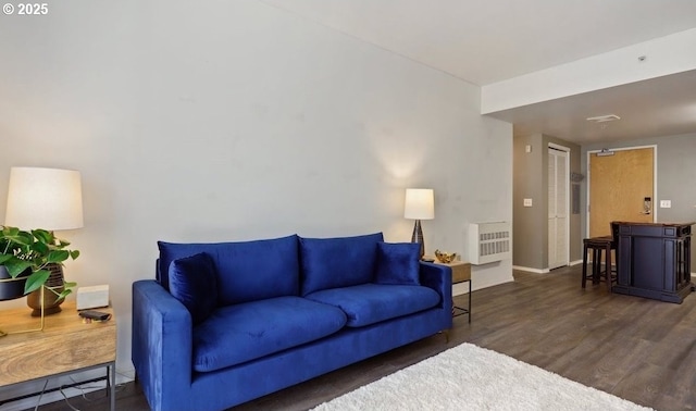 living area with baseboards, heating unit, and wood finished floors