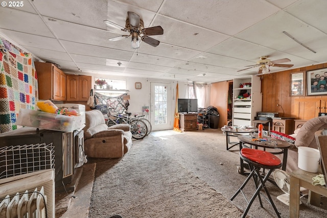 living room featuring light carpet, wood walls, and a ceiling fan