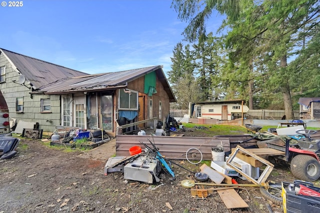 back of property featuring an outbuilding, metal roof, and fence