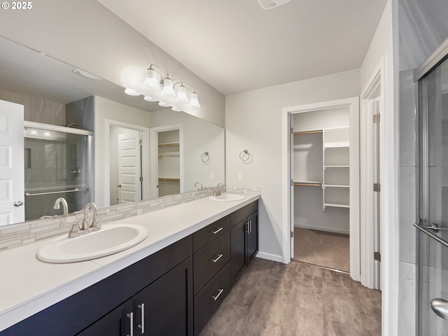full bathroom featuring a stall shower, double vanity, a sink, and a walk in closet