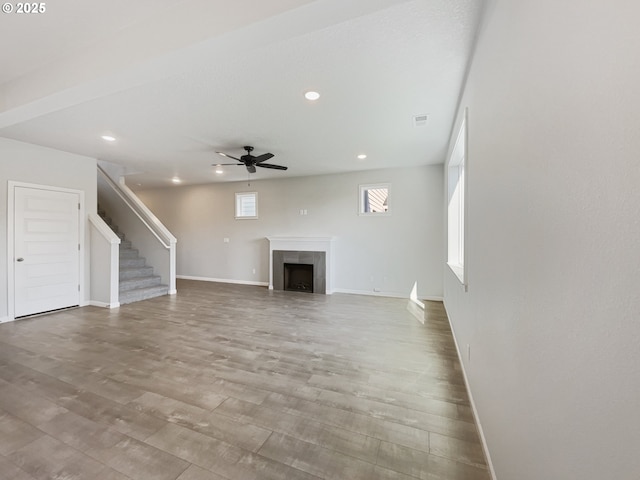 unfurnished living room featuring a ceiling fan, recessed lighting, wood finished floors, stairs, and baseboards