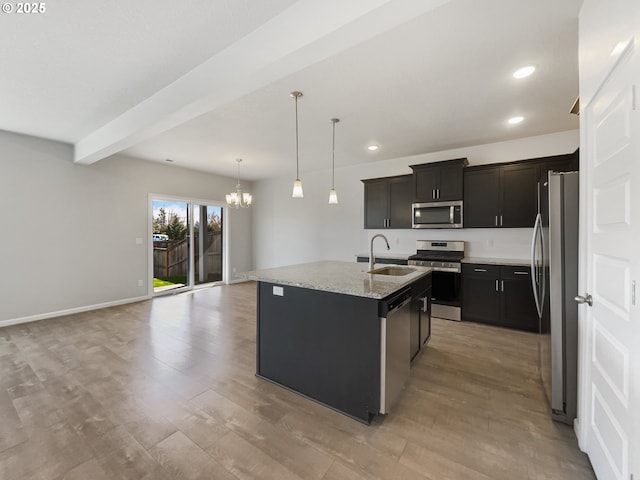 kitchen featuring a sink, appliances with stainless steel finishes, a chandelier, a center island with sink, and light wood-style flooring