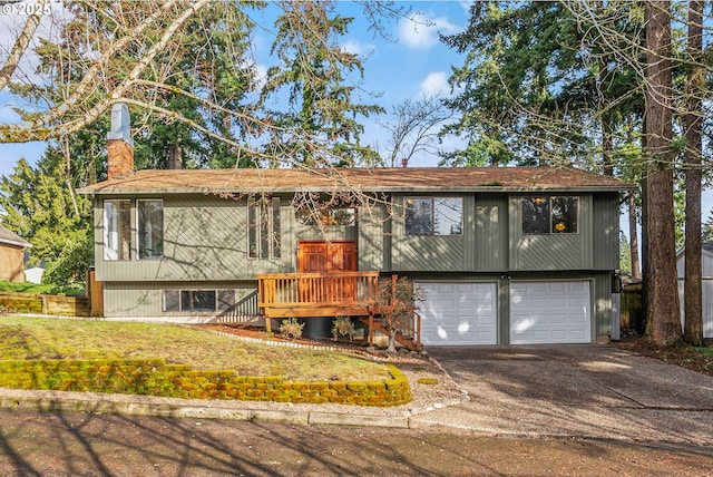 split foyer home with a front yard, driveway, a chimney, and an attached garage