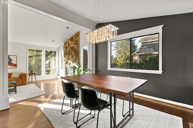 dining room featuring vaulted ceiling with beams, baseboards, a chandelier, and hardwood / wood-style floors