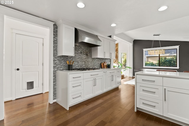 kitchen with stainless steel gas cooktop, wall chimney exhaust hood, light countertops, and white cabinets