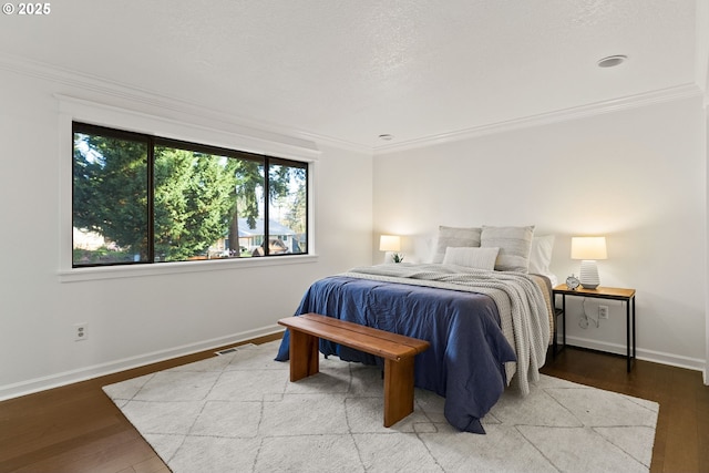 bedroom featuring ornamental molding, light wood finished floors, a textured ceiling, and baseboards