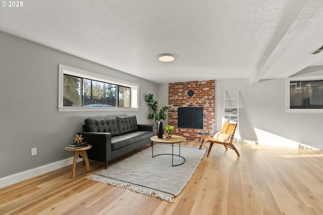 living area with a textured ceiling, a fireplace, light wood-style flooring, and baseboards