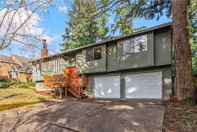 raised ranch featuring a chimney, concrete driveway, a deck, a garage, and stairs