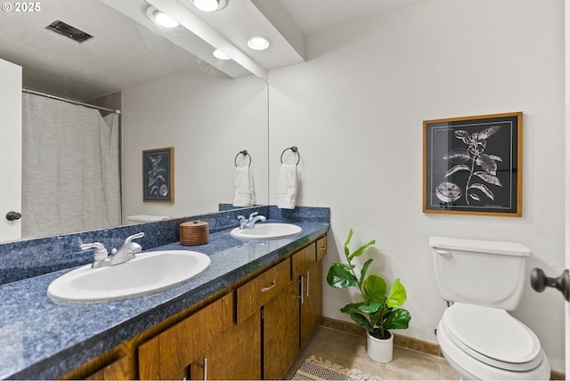 bathroom featuring visible vents, a sink, toilet, and double vanity