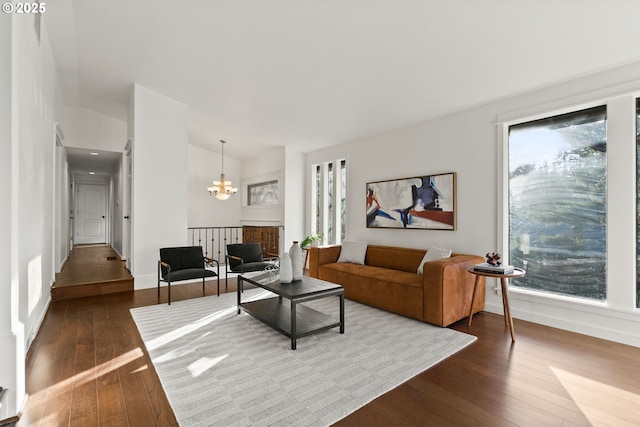 living area with an inviting chandelier, baseboards, vaulted ceiling, and dark wood-type flooring