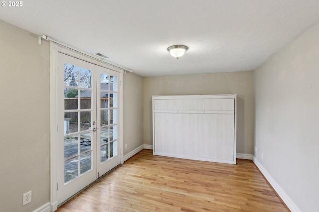 spare room featuring french doors and light wood-type flooring