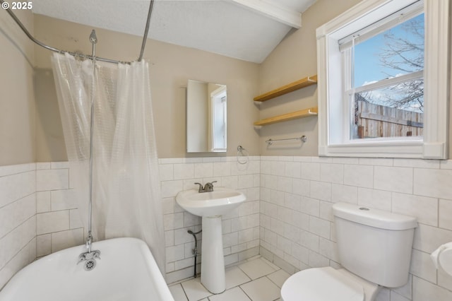 bathroom with toilet, tile walls, shower / bath combo with shower curtain, and tile patterned flooring