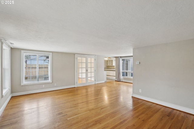 unfurnished living room featuring light wood-type flooring, a textured ceiling, and french doors