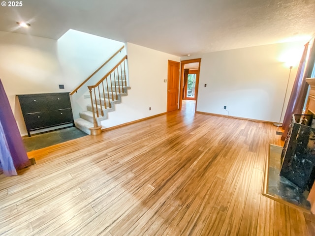 3241 SW Spring Garden St, Portland, OR 97219 - unfurnished living room with light wood finished floors, stairway, and a fireplace