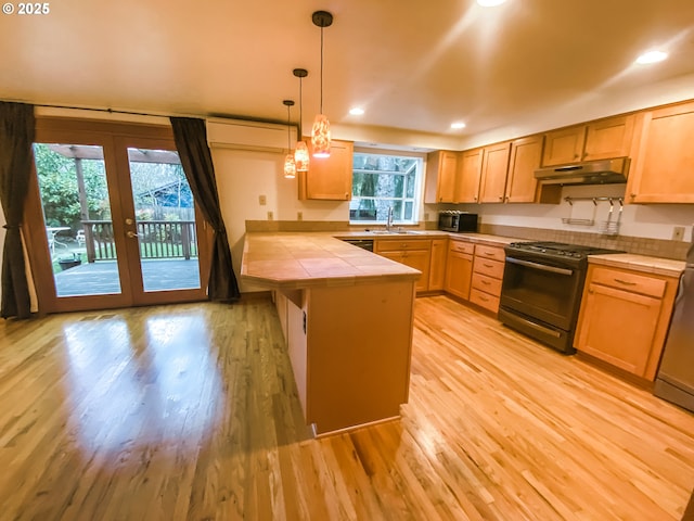 3241 SW Spring Garden St, Portland, OR 97219 - kitchen featuring black appliances, under cabinet range hood, a peninsula, tile counters, and light wood-type flooring