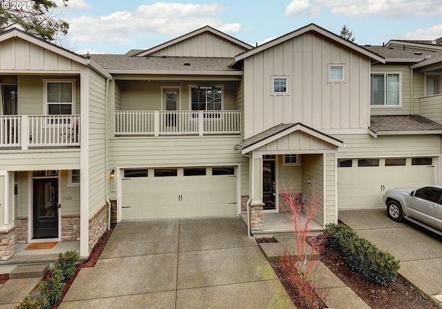 townhome / multi-family property with an attached garage, concrete driveway, stone siding, roof with shingles, and board and batten siding