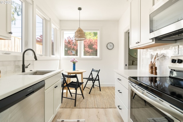 4633 SE 35th Ave Unit B, Portland, OR 97202 - kitchen with stainless steel appliances, a sink, light wood-style floors, backsplash, and light countertops