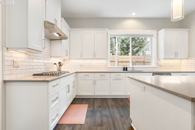 kitchen featuring decorative backsplash, range hood, appliances with stainless steel finishes, and white cabinetry