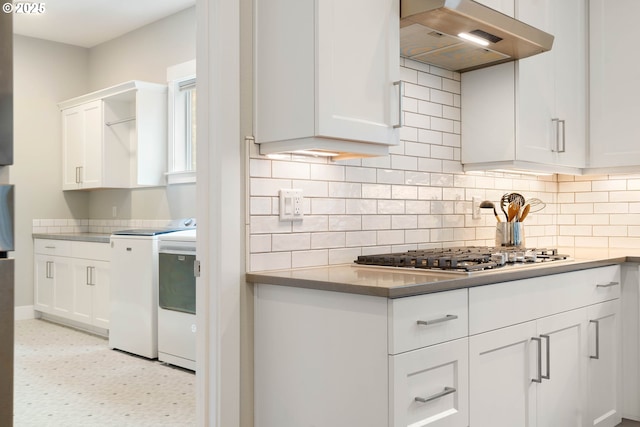 kitchen featuring stainless steel gas cooktop, white cabinetry, exhaust hood, decorative backsplash, and washing machine and clothes dryer