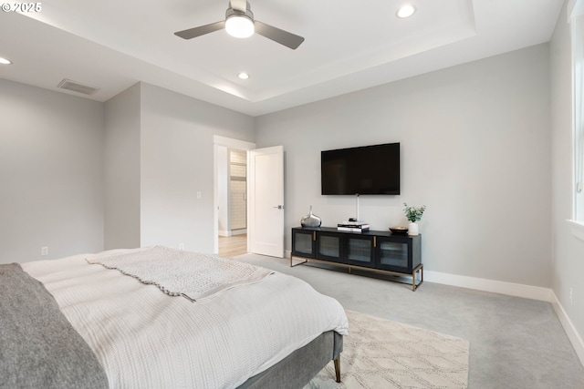 bedroom featuring visible vents, light carpet, a tray ceiling, recessed lighting, and baseboards