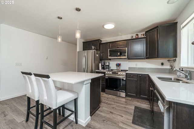 kitchen featuring a kitchen bar, light wood-style flooring, appliances with stainless steel finishes, and a sink