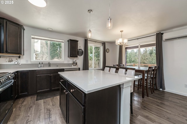 kitchen with dark wood-style flooring, light countertops, a wall mounted air conditioner, range with electric stovetop, and a center island