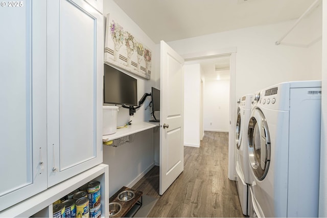 clothes washing area with laundry area, wood finished floors, and washer and clothes dryer