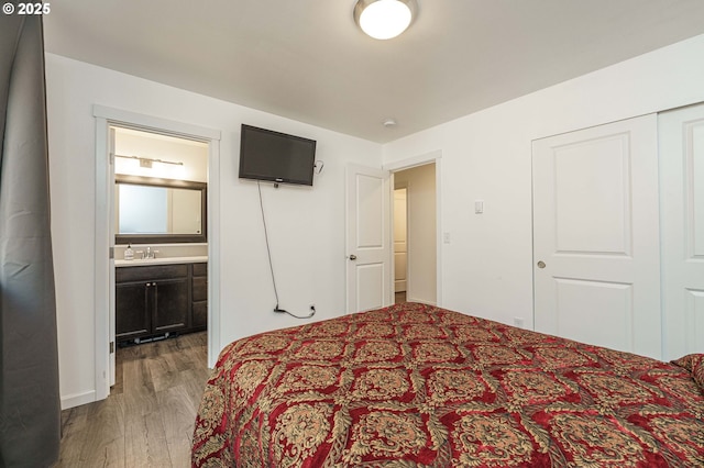 bedroom with a sink, ensuite bathroom, and wood finished floors