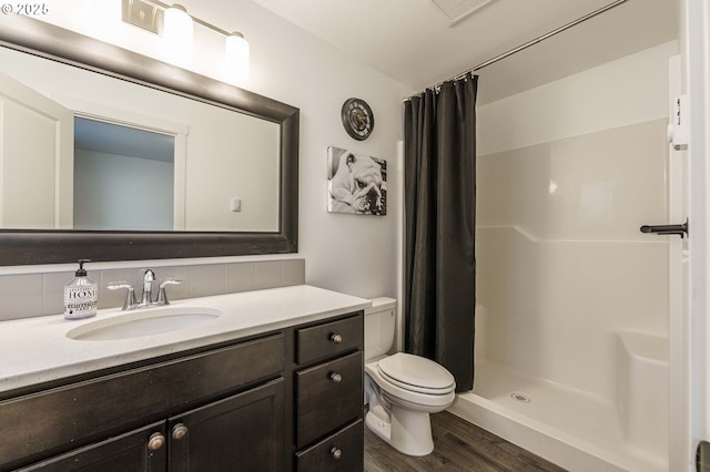 bathroom featuring tasteful backsplash, a shower stall, toilet, wood finished floors, and vanity