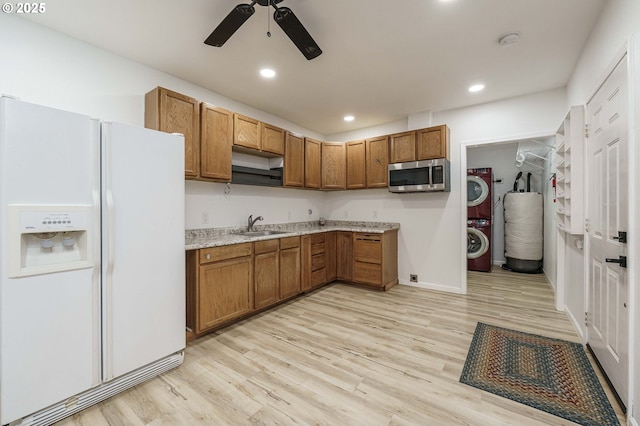 kitchen featuring a sink, stainless steel microwave, white refrigerator with ice dispenser, and brown cabinetry