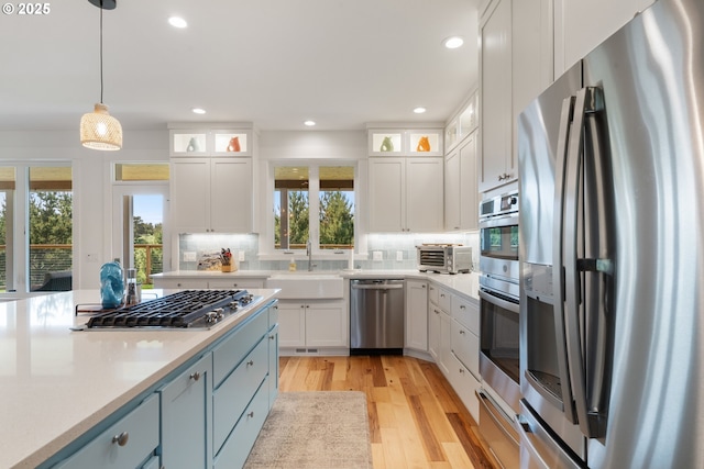 32996 Pacific Bellevue Ln, Warrenton, OR 97146 - kitchen with appliances with stainless steel finishes, a sink, light wood-style floors, decorative backsplash, and white cabinets
