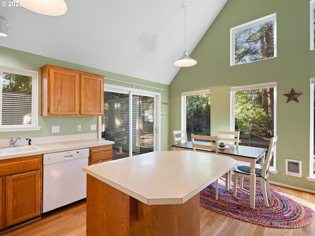 kitchen with sink, dishwasher, light hardwood / wood-style floors, a kitchen island, and decorative light fixtures