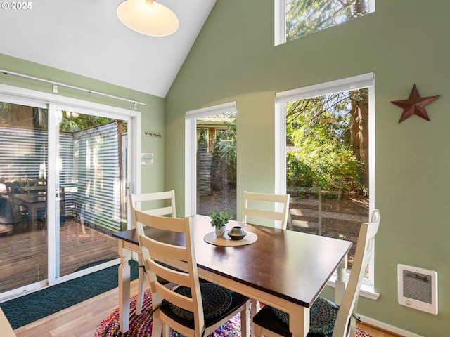 dining room featuring hardwood / wood-style flooring and high vaulted ceiling