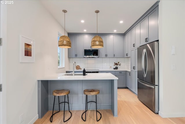 kitchen with pendant lighting, sink, decorative backsplash, appliances with stainless steel finishes, and kitchen peninsula