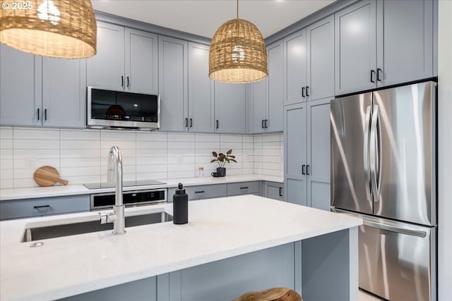 kitchen with decorative backsplash, stainless steel fridge, gray cabinets, and pendant lighting