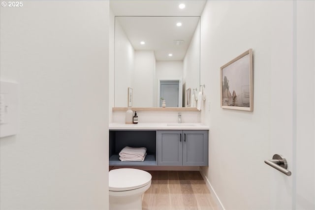 bathroom featuring vanity, wood-type flooring, and toilet