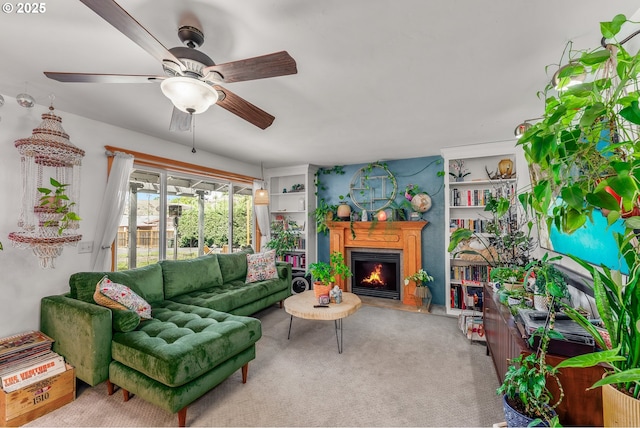 living area featuring carpet, a lit fireplace, and ceiling fan