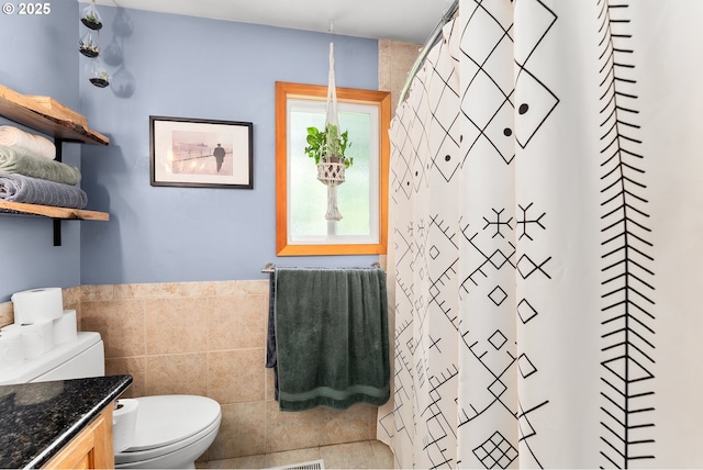bathroom featuring vanity, tile walls, a wainscoted wall, toilet, and visible vents