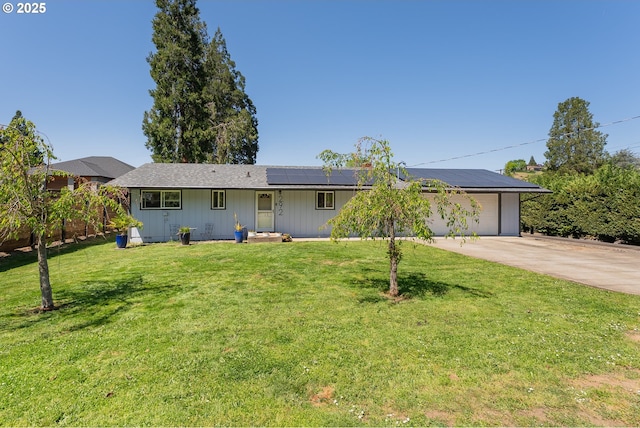 ranch-style home with a garage, driveway, a front yard, and solar panels