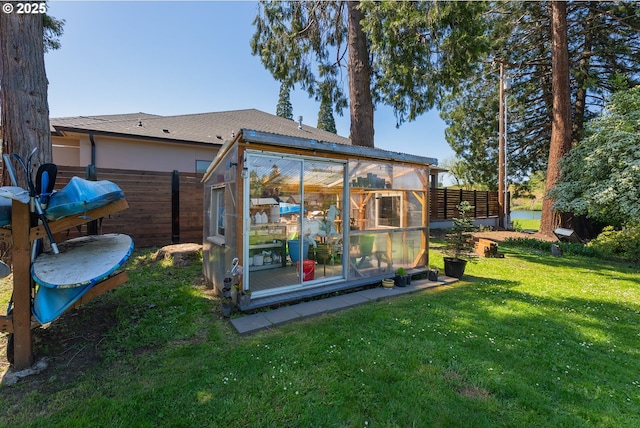 back of property featuring an exterior structure, an outdoor structure, fence, and a lawn