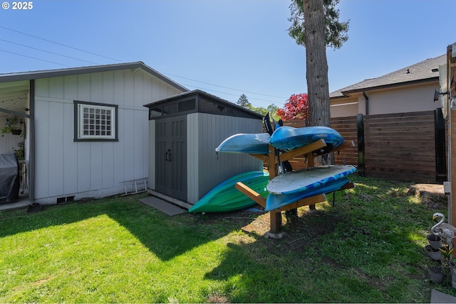 view of yard with an outdoor structure, fence, and a storage unit