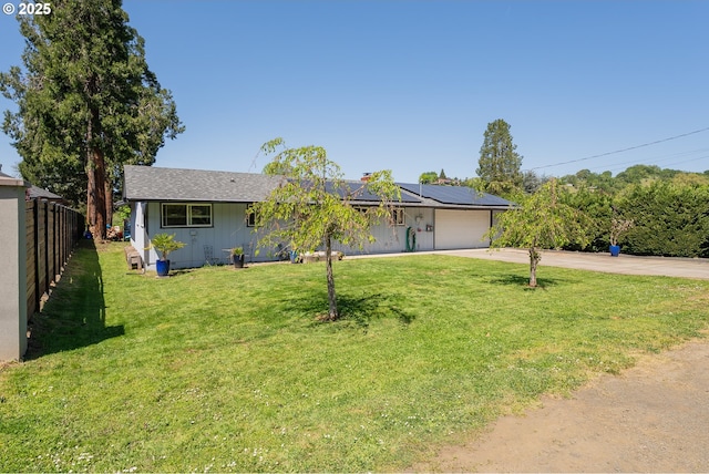 ranch-style home with roof mounted solar panels, fence, a front lawn, an attached garage, and driveway