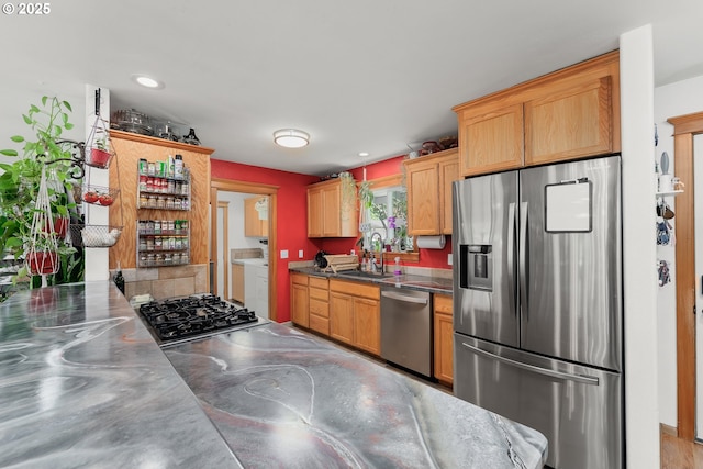 kitchen with washing machine and clothes dryer, a sink, stainless steel appliances, stainless steel counters, and recessed lighting