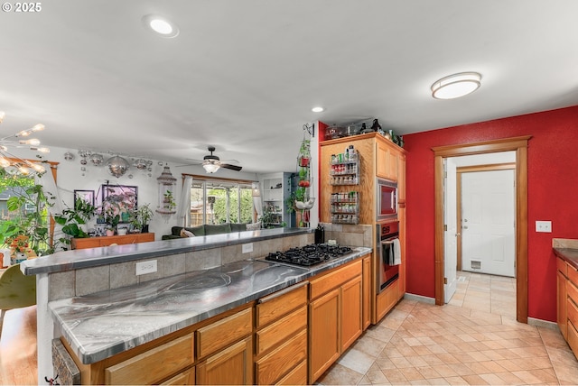 kitchen featuring brown cabinetry, ceiling fan, a peninsula, appliances with stainless steel finishes, and visible vents