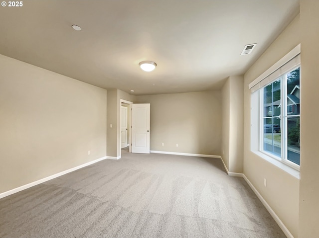 carpeted spare room featuring visible vents and baseboards